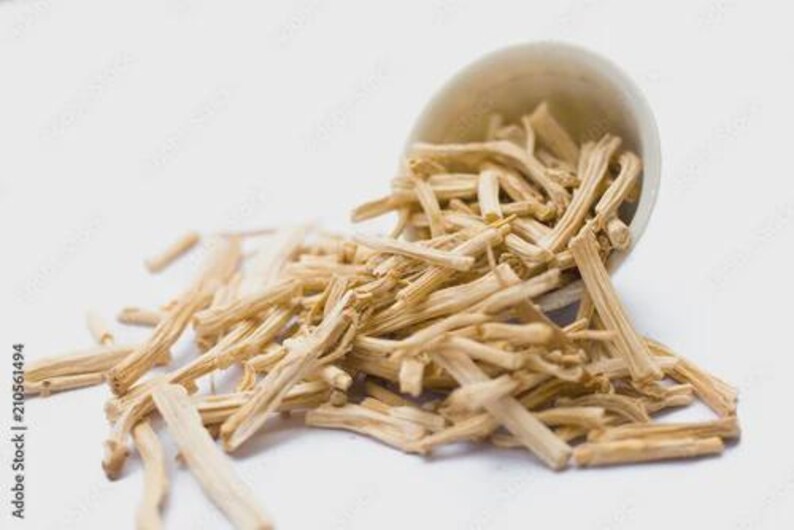 May include: A light beige ceramic bowl tipped over, spilling out numerous dried, light brown, stick-like pieces. The pieces are scattered on a white surface, creating a natural, earthy aesthetic. The image is well-lit, highlighting the texture of the items.
