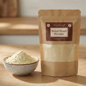 May include: A package of Safed Musli Powder and a small bowl filled with powder. The package is brown with a label that reads "Safed Musli Powder" and "Pure Ayurved Wellness." The bowl is white with a brown rim. The powder is light yellow.