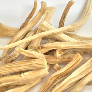 May include: Close-up of a pile of dried, light beige plant stems. The stems have a rough texture and varying shades of tan and brown. Some stems are curved, while others are straight. The image is well-lit, highlighting the natural details.