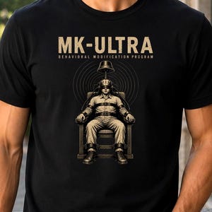 May include: Black t-shirt with the text "MK-ULTRA" above an illustration of a person strapped to a chair with a device on their head. The words "BEHAVIORAL MODIFICATION PROGRAM" are below the main text.