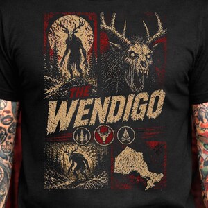 May include: Black t-shirt with a multi-panel design. The text "The Wendigo" is displayed above various panels showing a forest scene with a creature, a deer skull, and other graphic elements in red and tan.