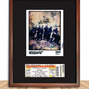 May include: Framed print featuring the band Slipknot, with signatures and graffiti-style art. Includes a concert ticket from the Subliminal Verses Tour at the Mid-America Center. The frame is dark brown.