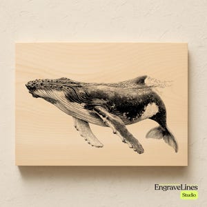 May include: A black and white illustration of a humpback whale swimming underwater, printed on a light-colored wooden plaque. The whale is detailed with visible fins and a tail, with water droplets visible above the surface. The text "EngraveLines Studio" is in the bottom right corner.