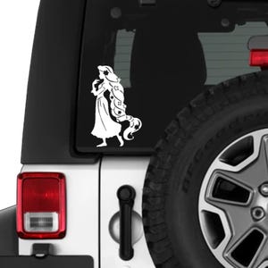 May include: White vinyl decal of a princess with long flowing hair, adorned with stars and flowers. The princess is wearing a long dress and is walking. The decal is applied to the rear window of a white vehicle.