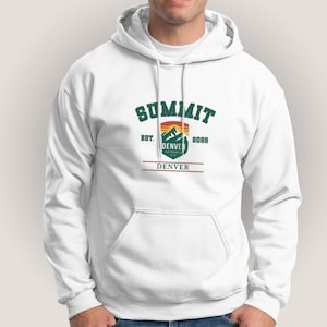May include: White hooded sweatshirt with a front pocket and drawstring. The front features the word "SUMMIT" in green arched lettering above a mountain graphic with the text "DENVER" and "EST. 2022".