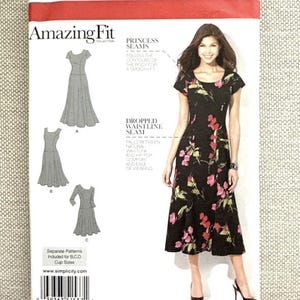 Puede incluir: Un sobre de patrón de costura Simplicity 1537 Amazing Fit con un vestido negro con estampado floral rosa y verde. El sobre muestra tres variaciones de vestido, información de tallas para Euro 36-44 y texto que detalla las costuras princesa y la costura de cintura caída.