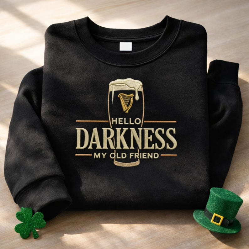 May include: Black sweatshirt with the phrase "HELLO DARKNESS MY OLD FRIEND" in gold lettering. The design includes a beer glass with a harp symbol. A green shamrock and a green leprechaun hat are on the bottom right and left.