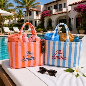 May include: Two striped canvas tote bags with the embroidered text "The Smiths". The left bag is orange and pink, containing a coral towel, a pink bottle, and a camera. The right bag is blue and white, containing a blue towel and a straw hat.