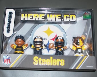 May include: A boxed set of Little People figures featuring the Pittsburgh Steelers. The set includes four figures in black and gold uniforms, with the words "HERE WE GO" and "Steelers" displayed on the packaging.