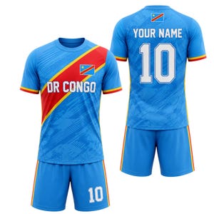 May include: A blue soccer uniform with red and yellow accents. The jersey features the text "DR CONGO" and the number "10". The back of the jersey has the text "YOUR NAME" and the number "10". The uniform includes a jersey and shorts.