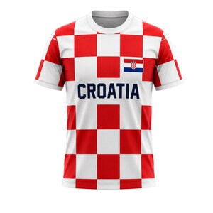 May include: A white and red checkered t-shirt with the word "CROATIA" in navy blue block letters. The shirt features the Croatian flag on the chest. The shirt has short sleeves and a crew neck.