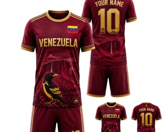 May include: Maroon soccer uniform with gold accents, featuring the word "VENEZUELA" and the Venezuelan flag. The jersey displays a landscape design with a bird. The shorts have the number 10. Additional smaller views are also shown.