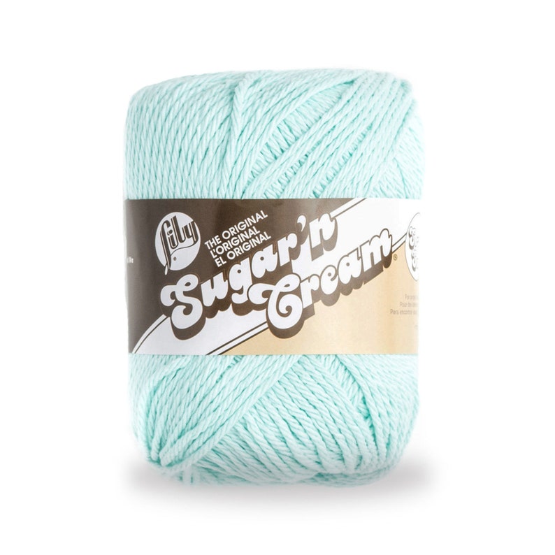 May include: A skein of light blue Lily Sugar'n Cream yarn. The yarn is wrapped around a brown label with the text "The Original L'Original El Original Sugar'n Cream".