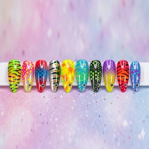 May include: A set of ten artificial nails, each painted with a unique fish-inspired design. The nails feature vibrant colors like neon green, pink, red, silver, yellow, and blue, with patterns including stripes, scales, and dots. Each nail has a small, silver accent.