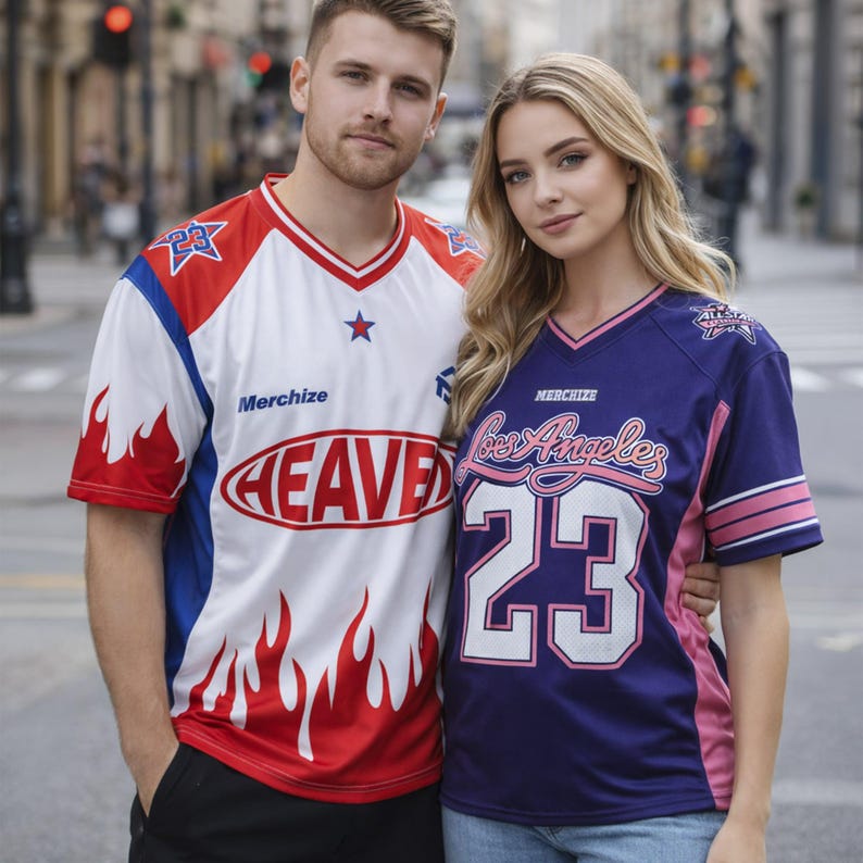 May include: Two people wearing matching jerseys. One jersey is white with red and blue accents, the word "HEAVE" in a red oval, and the number "23". The other jersey is navy blue with pink accents, the words "Los Angeles" and the number "23".