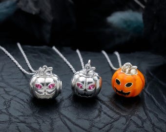 May include: Three Halloween-themed pendant necklaces. Two silver pumpkin pendants with pink gem eyes and a smiling face. The third pendant is an orange pumpkin with a black smiling face. All pendants are on silver chains.