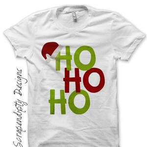 May include: White t-shirt featuring a Christmas-themed "Ho Ho Ho" design in green and red. A Santa hat graphic is above the first "Ho". The text "Scrapendisty Designs" is printed vertically on the left side of the shirt.