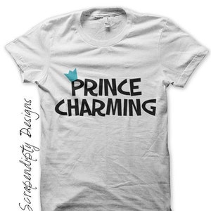 K&ouml;nnte beinhalten: Wei&szlig;es T-Shirt mit dem Text "Prince Charming" in schwarzen Buchstaben und einer blauen Krone &uuml;ber dem Wort "Prince".