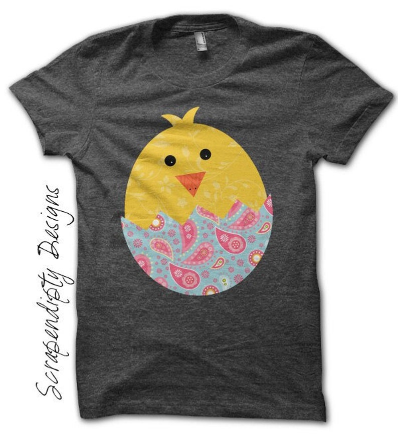 May include: A dark gray t-shirt with a yellow chick peeking out of a blue, pink, and green patterned egg.