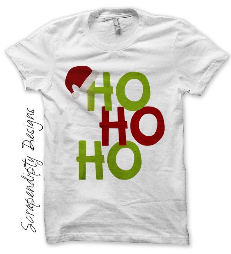 May include: White t-shirt featuring a Christmas-themed "Ho Ho Ho" design in green and red. A Santa hat graphic is above the first "Ho". The text "Scrapendisty Designs" is printed vertically on the left side of the shirt.
