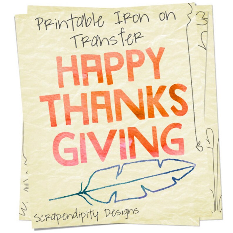 May include: Printable iron-on transfer design featuring the text "Happy Thanksgiving" in a watercolour style with a red, orange, and pink colour scheme. A blue feather is drawn below the text. The text "Scrapendipity Designs" is at the bottom of the design.