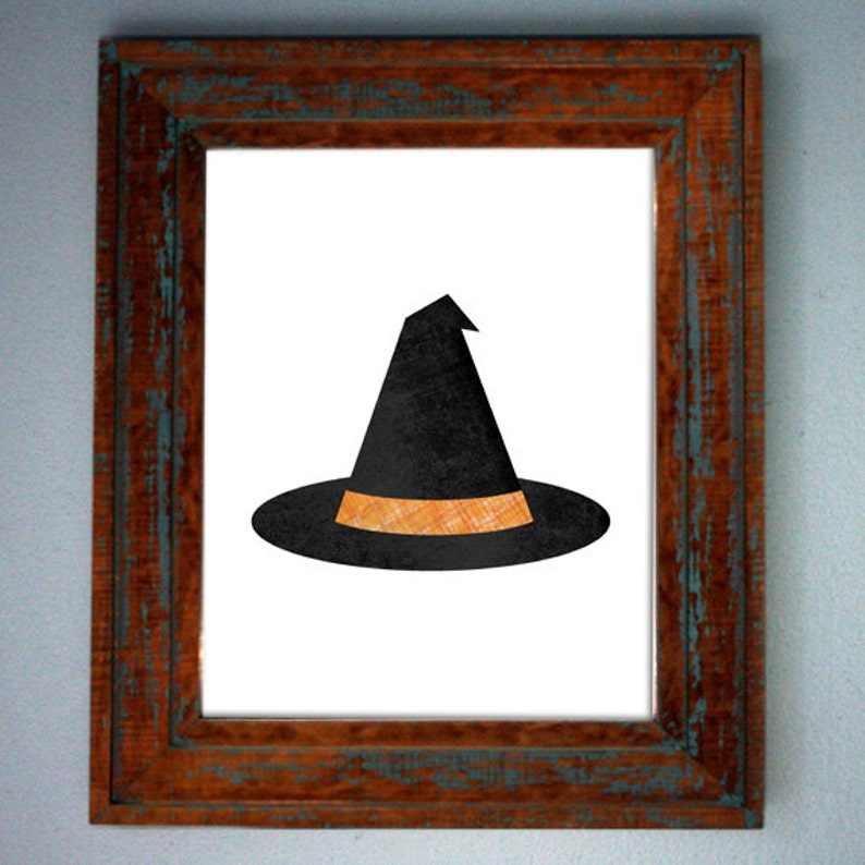 May include: A black witch hat with an orange band in a brown wooden frame.
