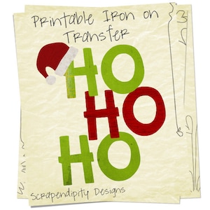 May include: A festive iron-on transfer design on a textured, pale yellow background. The design features the words "HO HO HO" in green and red, with a Santa hat above the first "HO". The text "Printable Iron on Transfer" and "Scrapendipity Designs" are also visible.