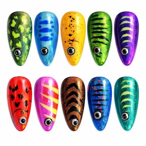 May include: Ten colorful, teardrop-shaped fishing lures with eye details. The lures feature various patterns and colors, including green with yellow spots, blue with blue stripes, and yellow with black spots. Each lure has a metallic sheen.