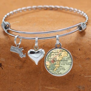 May include: A silver charm bracelet with three charms: a heart, a state of Massachusetts outline, and a vintage map of Gloucester, Massachusetts.