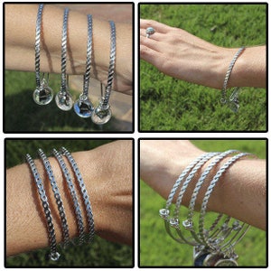 Puede incluir: Cuatro pulseras de plata con un dise&ntilde;o trenzado y un peque&ntilde;o dije en cada una. Los dijes son redondos y tienen una apariencia de vidrio transparente.