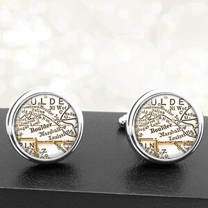 May include: A pair of silver cufflinks with a vintage map of Boulder, Colorado, printed on the front. The map is in black and white and shows the city's streets and landmarks.