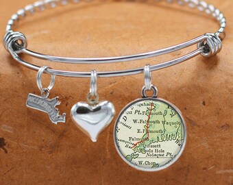 May include: A silver charm bracelet with three charms: a heart, a state of Massachusetts outline, and a round charm with a vintage map of Falmouth, Massachusetts.