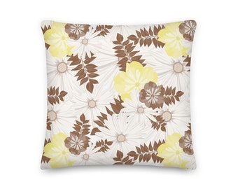 Puede incluir: Una almohada blanca con un patrón floral con hojas marrones y flores blancas y amarillas.