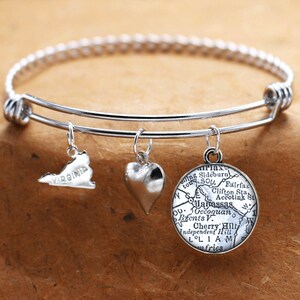 May include: A silver expandable bangle bracelet with three charms: a heart, a map of Virginia, and a map of the area around Occoquan, Virginia. The map charm has the words "Wapassas", "Occoquan", "Independent Hill", "Cherry Hill", "LOLIA", and "fries" on it.