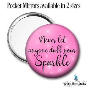 Puede incluir: Un espejo compacto rosa con marco plateado y el texto "Never let anyone dull your Sparkle" en letras negras. El fondo es rosa con purpurina blanca.