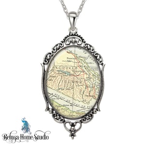 May include: A silver pendant necklace featuring a vintage map of Vancouver Island, British Columbia, Canada. The map is surrounded by an ornate silver frame with a heart-shaped bail.