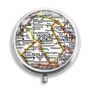 May include: A round, silver pill box with a map of Virginia inside. The map is colorful and shows the locations of various towns and cities. The pill box is a great way to keep your medication organized and on the go.