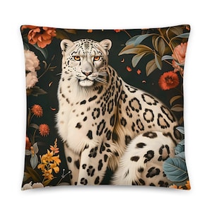 May include: Square throw pillow featuring a snow leopard illustration. The leopard is white with black spots and orange eyes, set against a dark background with floral elements in shades of orange, pink, and green.