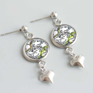May include: A pair of silver earrings with a map of Fresno, California, in the center of each earring. Each map is surrounded by a silver circle and hangs from a silver heart charm.