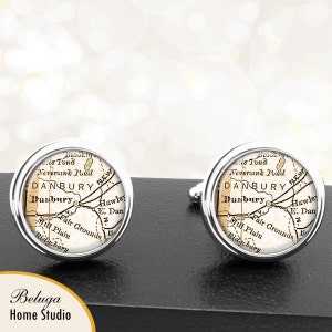May include: A pair of silver cufflinks featuring a vintage map of Danbury, Connecticut. The map is printed in brown and white on a white background. The cufflinks are a great way to show your love for your hometown.
