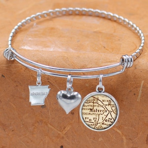 May include: A silver expandable bracelet with three charms: a heart, a state of Arkansas outline, and a vintage map of Malvern, Arkansas.