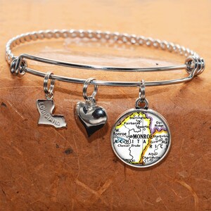Peut inclure: Un bracelet à breloques en argent avec trois breloques : un cœur, une carte de la Louisiane et une carte de Monroe, en Louisiane.
