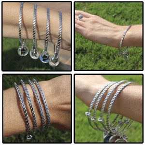 May include: Four silver bangle bracelets with a twisted design. The bracelets are stacked on a person's wrist.