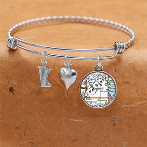 Puede incluir: Un brazalete de plata con tres dijes: un corazón, un contorno del estado de Minnesota y un mapa de la zona de los lagos Brainerd en Minnesota.