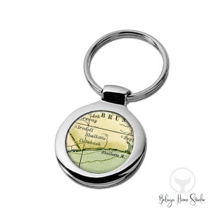 May include: A silver key chain with a round, silver-rimmed charm featuring a vintage map of Shallotte, North Carolina. The map shows the town's location on the coast, with the text "BRUNSWICK" and "Shallotte R." visible.