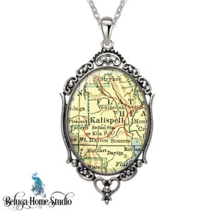 May include: Silver-toned pendant necklace with an oval-shaped pendant featuring a vintage map design. The map shows the area around Kalispell, Montana. The pendant has an ornate, filigree-style frame and a delicate chain.
