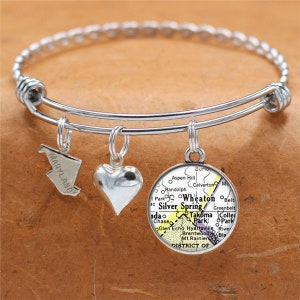May include: A silver bangle bracelet with three charms: a heart, a state of Maryland outline, and a map of Wheaton, Silver Spring, and Takoma Park, Maryland.