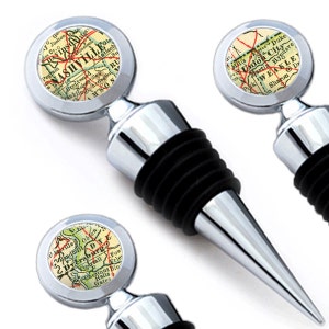 May include: Three silver bottle stoppers with a black rubber stopper. Each stopper features a vintage map of a different city: Nashville, Tennessee; Dyersburg, Tennessee; and Union City, Tennessee.