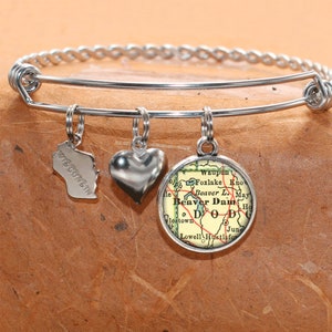 May include: A silver charm bracelet with three charms: a heart, a state of Wisconsin outline, and a round charm with a vintage map of Beaver Dam, Wisconsin. The map shows the town of Beaver Dam, Foxlake, Waupun, and surrounding areas.
