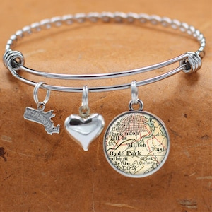 May include: A silver charm bracelet with three charms: a heart, a map of Boston, Massachusetts, and a map of the Boston area. The map charms are both in a vintage style.